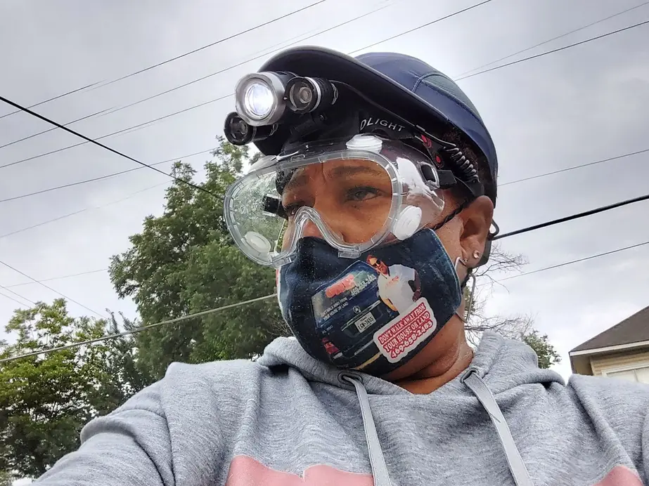 One Stop Shop inspector in a hard hat with a headlamp, safety goggles and a respirator mask printed with the company logo